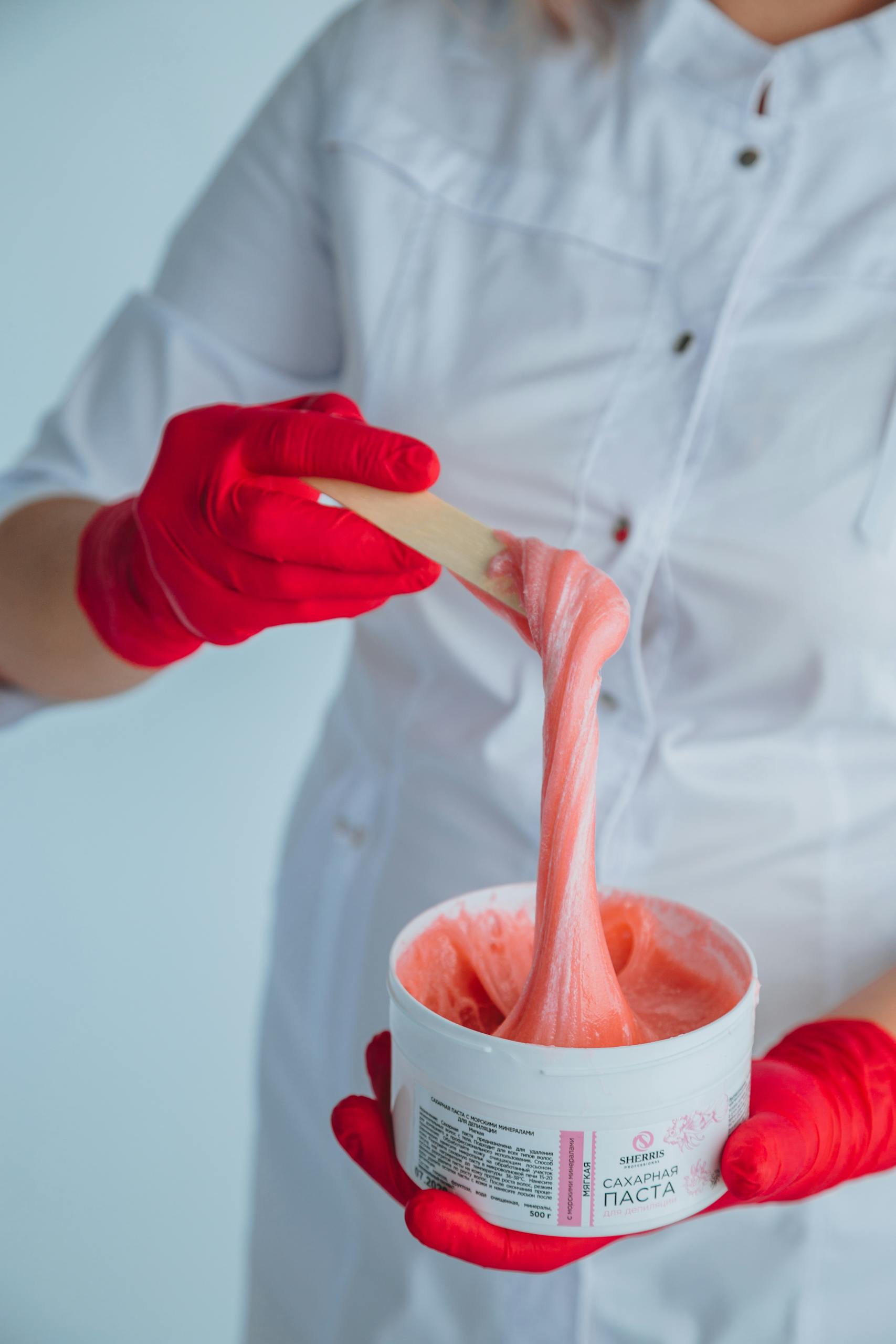 Close-up shot of a sugaring expert applying paste, showcasing cleanliness and precision.